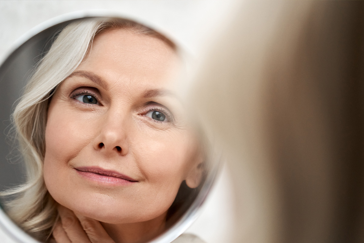 An older woman smiling at herself in a mirror